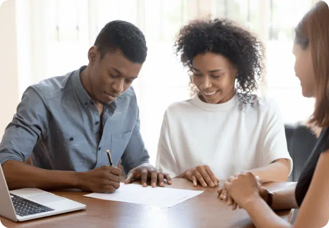 A man and a woman signing a contract, financially planning as a couple with an adviser.