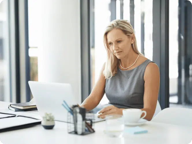 Woman sitting at her desk, working on laptop to discuss long-term holistic planning with clients.