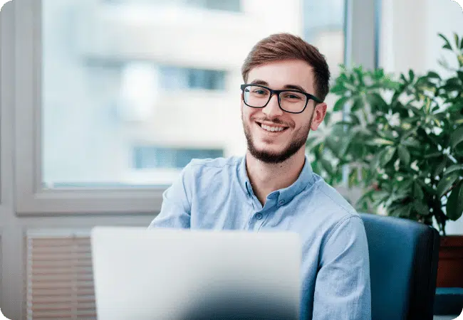 Man smiling with glasses with his laptop.