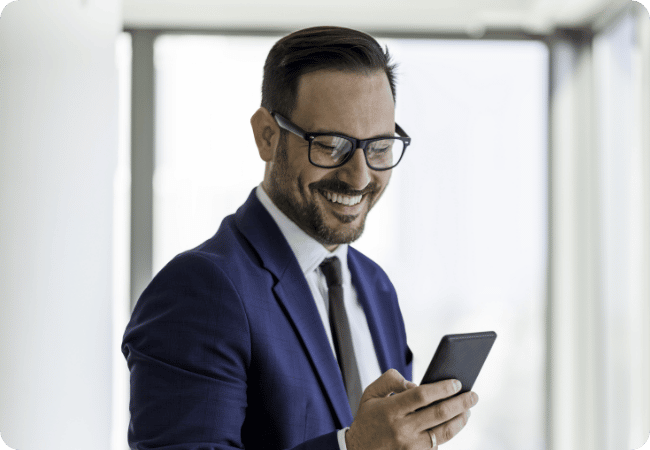 man wearing glasses smiling at his phone
