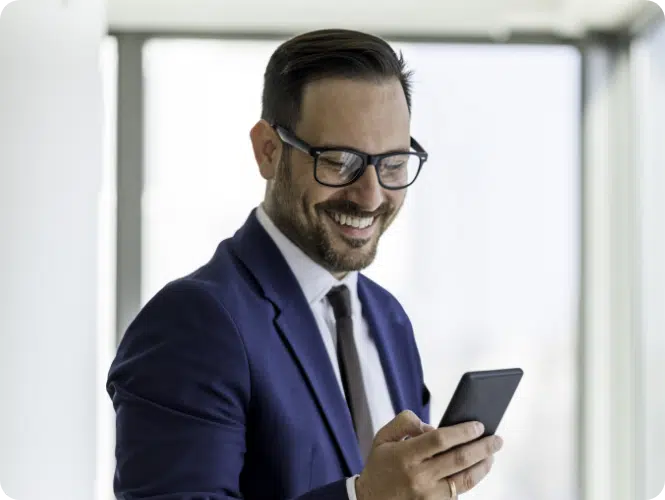 man in suit smiling at mobile phone